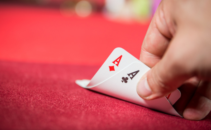 德州撲克最強起手牌AA:玩家手中握有兩張A,紅色絨布牌桌背景
